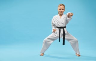 Menina faixa preta em karatê fazendo um golpe